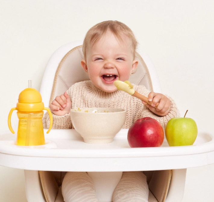 stock-photo-baby-wearing-knitted-sweater-sitting-in-high-chair-and-feels-hungry-holding-spoon-and-eating-puree-2169821577@2x